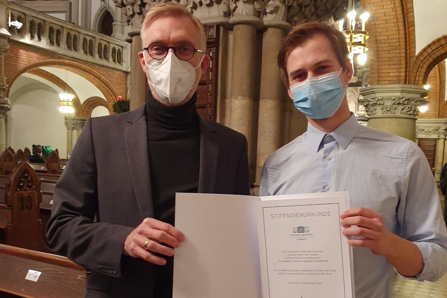 Tobias Klinger erhält in einer Festveranstaltung in der Petrikirche, Dezember 2022, die Urkunde für das vom InnoMat IWW e.V. gestiftete Deutschlandstipendium. Aufgrund der Corona-Pandemie war das Tragen von Schutzmasken angeordnet.